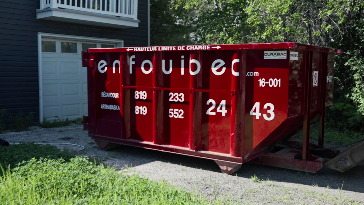 Un conteneur rouge Enfouibec installé devant une maison
